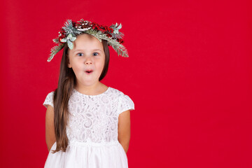 mock up amazing girls in a Christmas wreath and white dress on a red background with space for text.