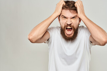 bearded man gesturing with his hands in a white t-shirt aggression light background