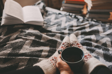 cozy winter day at home with cup of hot tea, book and warm socks. Spending weekend in bed, seasonal holidays and hygge concept