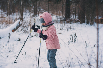 happy child girl skiing in winter snowy forest, spending holidays outdoor. Active winter sports.