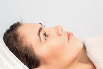 Fototapeta na wymiar Side view portrait of pensive young woman lying and waiting for cosmetic procedure in beauty salon