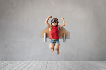 Child with jetpack jumping against grey concrete background