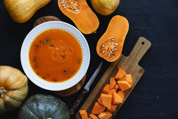Top view of pureed pumpkin soup in a white bowl on dark table