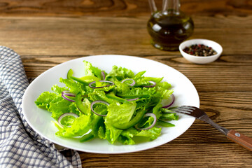 Fresh Green salad in white plate on dark rustic background. Selected focus.
