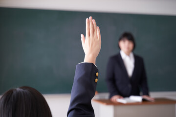 教室で手を挙げる日本人女子中学生