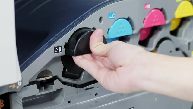 Close-up of replacing a black toner cartridge for color laser printer, male hand pulls on a cartridge