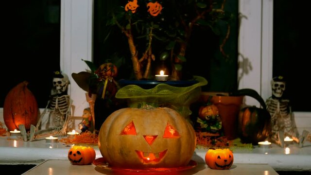 Home decoration with spooky glows halloween pumpkin head Jack Lantern face and burning candle. Carved eyes, mouth. Traditional Halloween symbol. Medium plan.