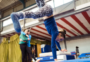 Young female circus school student performs cartwheel observed by her classmates