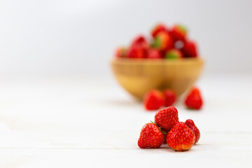 Heap of fresh strawberries with wooden dish in background. Pile of fresh nutritious raw fruit on...