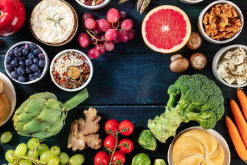 Vegetarian food background design with copy space, a flatlay, shot from above. Fruit and vegetables, cheese, nuts, rice on a dark blue wooden background