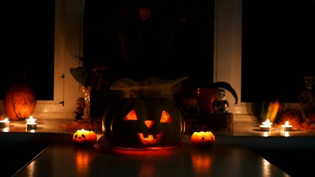 Home decoration with spooky glows halloween pumpkin head Jack Lantern face and burning candle. Carved eyes, mouth. Traditional Halloween symbol. Medium plan.