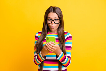 Photo portrait of young schoolgirl with amazed face using smartphone typing staring isolated on...