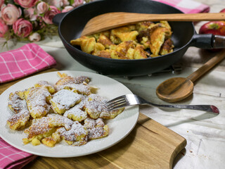 austrian pancakes. Kaiserschmarrn served with powdered sugar on a plate and pan