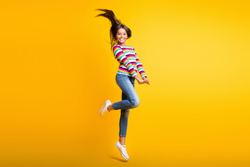 Fototapeta na wymiar Full length body size photo of jumping schoolgirl with long brunette hair smiling cheerfully isolated on vivid yellow color background