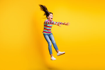 Fototapeta na wymiar Full length body size photo of kicked up schoolgirl in windy weather isolated on vivid yellow color background