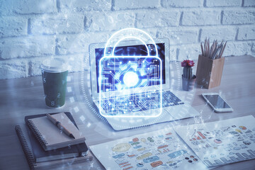 Double exposure of desktop with computer and lock icon hologram. Concept of data safety.