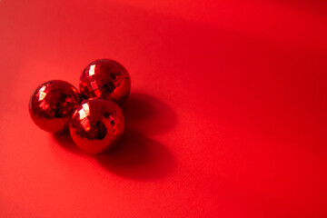 Three red Christmas balls on red background with contrasting shadows. Merry Christmas card. Concept of celebrating new year. Copy space