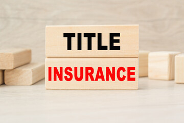 the word TITLE INSURANCE is written on a wooden cubes structure. Cube on a bright background. Can be used for business, marketing, financiaL, INSURANCE concept. Selective focus.