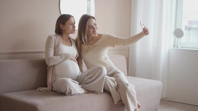 Young woman is taking photo her pregnant friend. High quality 4k footage