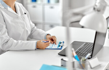 medicine, healthcare and profession concept - female doctor in white coat with laptop computer and medical report at hospital
