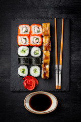  Japanese rolls on black slate board and black background top view, vertical photo
