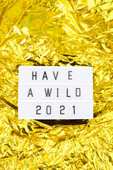Light box with an inscription have a wild 2021 on a bright gold background.
