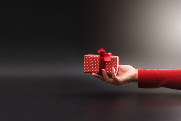 Woman hand give a present on black background, Christmas Boxing Day concept