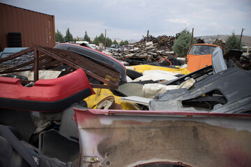 Car bumpers, used rims, rusty vehicle exhausts, doors and other parts, stacked in an unarranged order.Awaiting dismantling, recycling or re-sale. At a car cemetery.