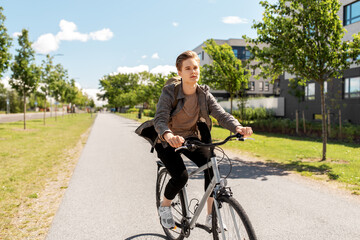 lifestyle, transport and people concept - young man or teenage student boy with backpack riding bicycle on city street