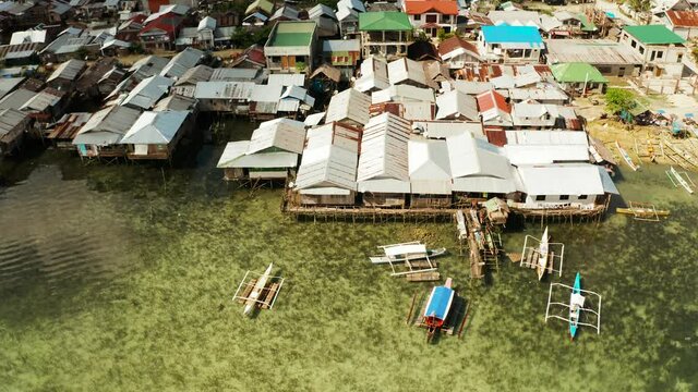 Fishing village with wooden houses standing on stilts in the sea from above. Dapa, Siargao, Philippines.