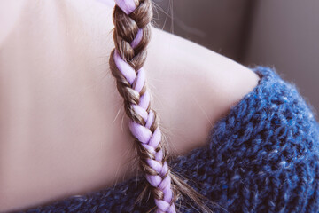 Girl in soft warm dark blue knitted sweater and a pigtail with pink kanekalon