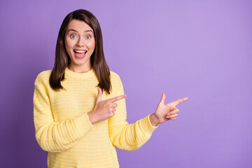 Photo portrait of excited girl pointing two fingers at blank space isolated on vivid violet colored background