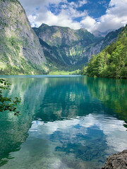 Breathtaking view of green turquoise crystal clear alpine lake Obersee Koenigssee surrounded by mountains Alps in Bavaria, Germany