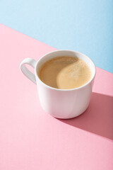 cup of coffee on a pastel pink and blue background, photography with contrast shadow