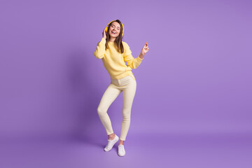 Fototapeta na wymiar Full length body size photo of dreamy brunette listening to music wearing modern yellow earphones dancing isolated on vibrant violet color background