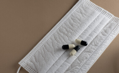 apsules sitting on top of a surgical face mask. Covid-19 medication. 
