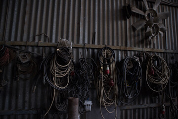 Various wires hanging on a metal beam. Two metallic fans of a heavy machinery on the right.