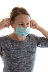 Woman putting a medical mask on. Isolated on a bright background. 