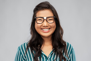 people, education and school concept - portrait of happy asian woman in broken glasses with patch or student over grey background