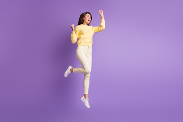 Fototapeta na wymiar Photo portrait full body view of celebrating woman jumping up holding fists high isolated on bright purple colored background