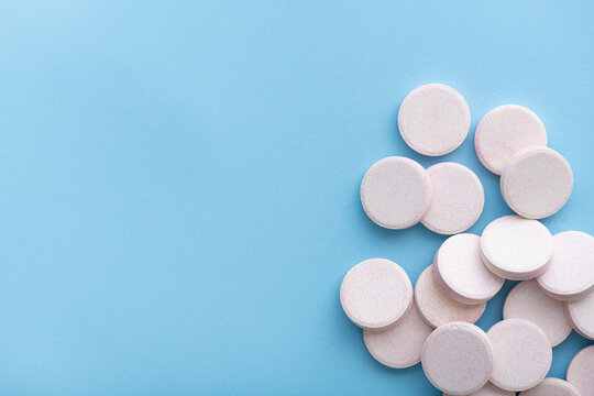 effervescent tablets on pastel blue background, top view, copy space
