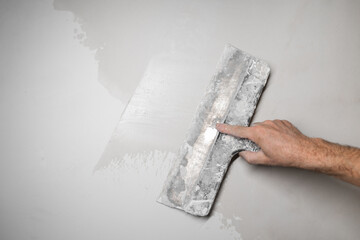 Female hand repairs wall. Craft, putty.  Man putty plasterboard