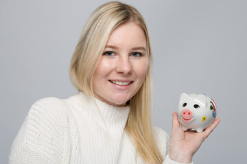 Fototapeta na wymiar Young happy woman with a piggy bank / porcelain bank in her hand