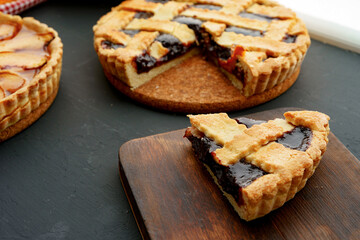 Cut slice of berry tart pie on black table