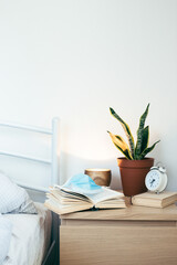 Bedside wooden table with medical mask and home decor. Lockdown concept.