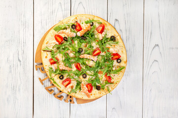 Pizza covered with roquette and shrimps on wooden table, top view with copy space.