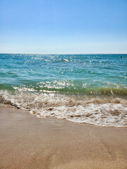 The sea is agitated. Beautiful waves on a sandy beach. Sea, waves, and blue sky.