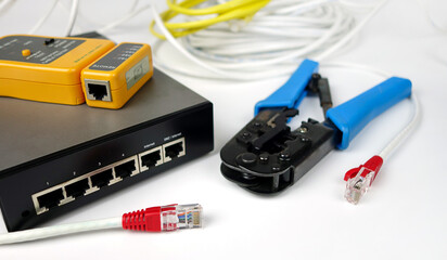 Network switch, ethernet cable, crimper and RJ45 cable tester isolated on white background.