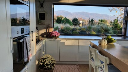 Piękna duża biała kuchnia z oknem panoramicznym, i pięknym widokiem, wyspa w kuchni - obrazy, fototapety, plakaty