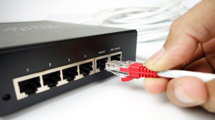 Man's hand connects the Internet cable to the socket of the router.	
